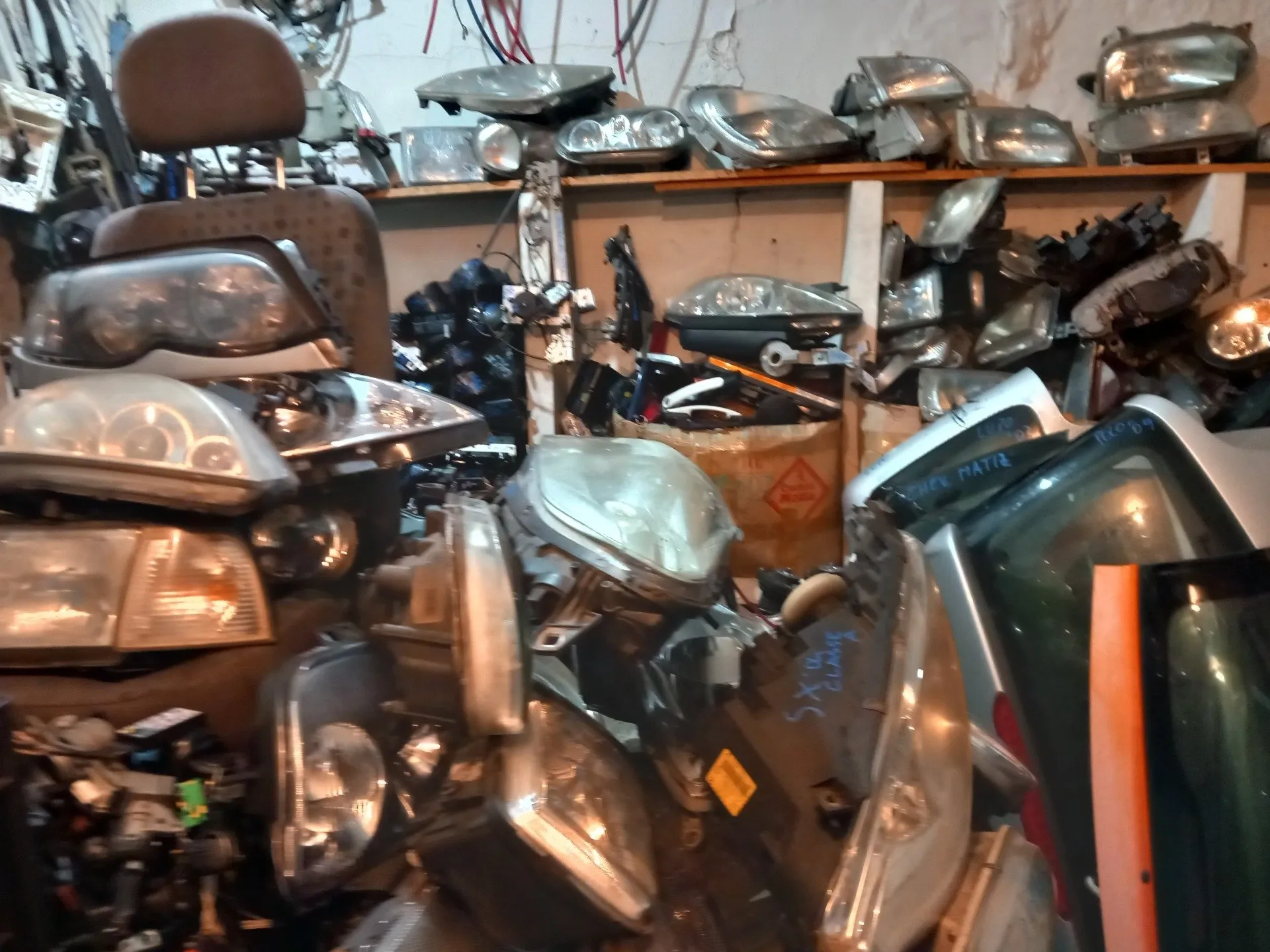 Fanali, gruppi ottici e parti di carrozzeria usate sugli scaffali del magazzino di Genova